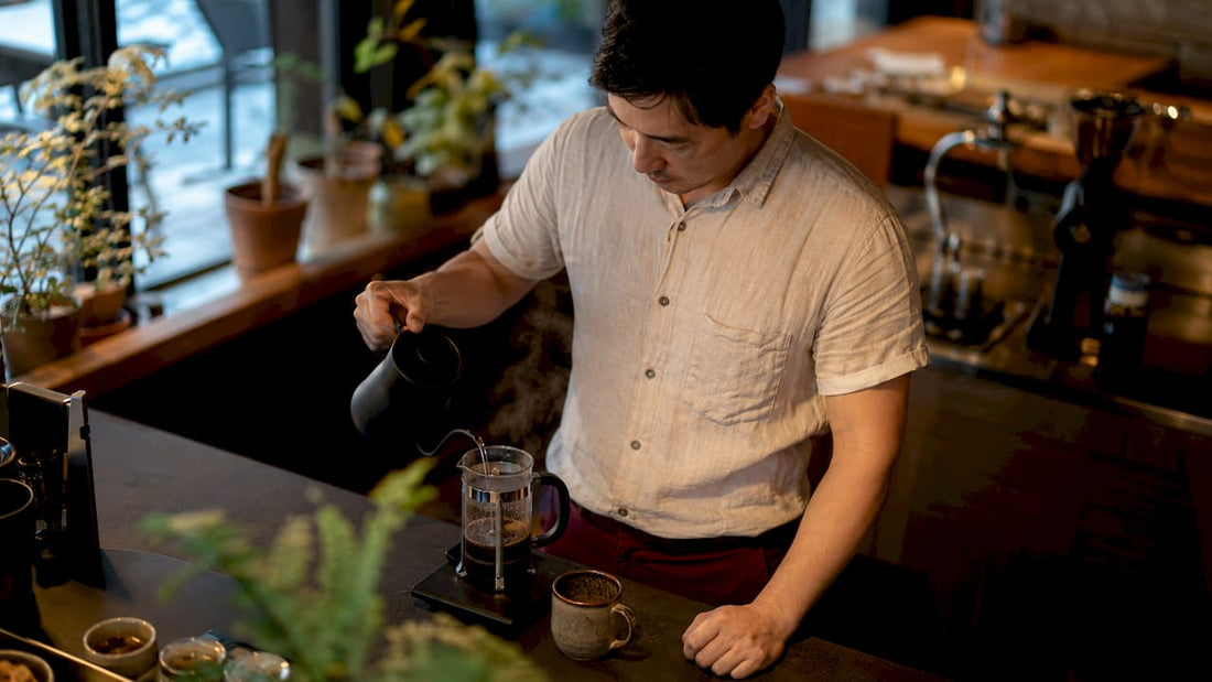 Home barista brewing French press coffee in kitchen