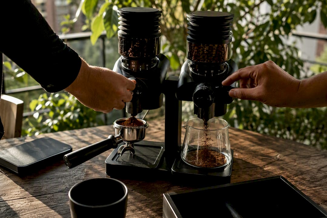 Hands adjusting coffee grinder settings for espresso and filter roasts