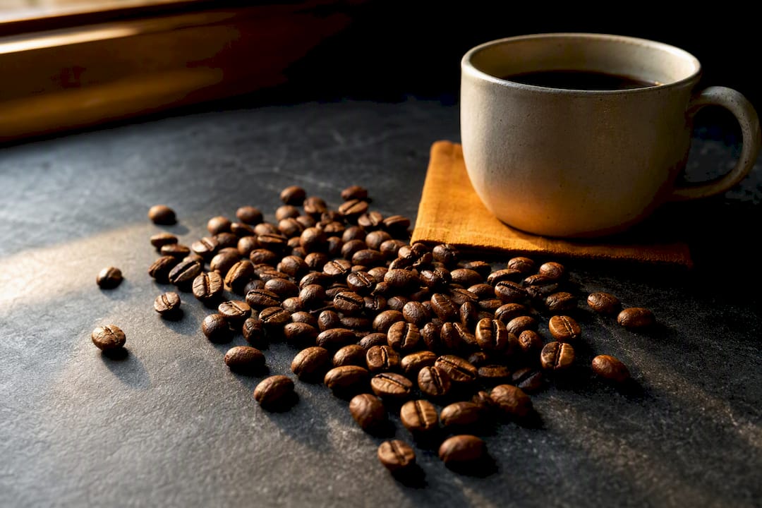 Medium roast Arabica beans beside coffee cup
