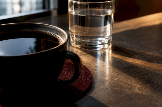 Black coffee beside water in morning light